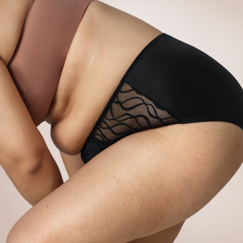 Woman wearing TENA Silhouette Washable Absorbent Underwear and bending forward.